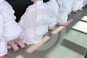 Group of children in kimono sitting on tatami on martial arts training seminar