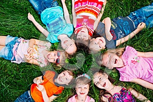 A group of children lying on the green grass in the Park. The interaction of the children.