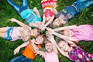 A group of children lying on the green grass in the Park. The interaction of the children.