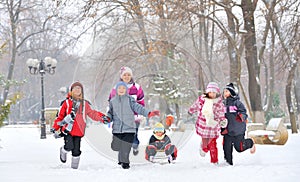 Gruppo di bambini e di adulti a giocare sulla neve in inverno, la ragazza tirando sorella di neve, la slitta.