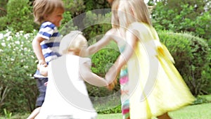 Group Of Children Playing Ring Around The Rosy In Garden