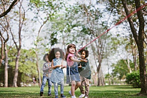 Group of children playing tug of war at the park.