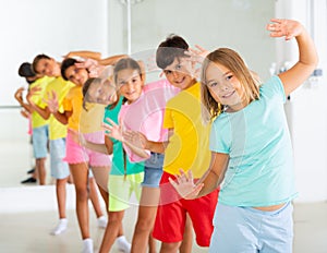 Group of children rehearsing movements of ballet in classroom