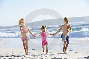 Group Of Children Running Along Beach In Swimwear