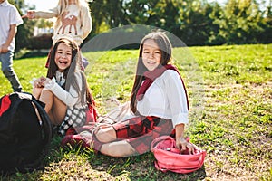 A group of children of school and preschool age are sitting on the green grass in the park.