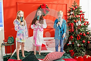 Group of children sing and dance at pajama party during Christmas holidays. Christmas music