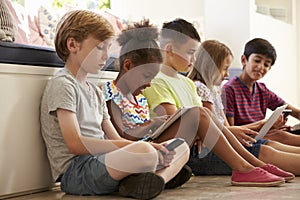 Group Of Children Sit On Floor And Use Technology