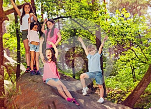 Group of kids cheering standing on stone in forest