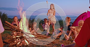 Group of children sitting around fire at twilight.