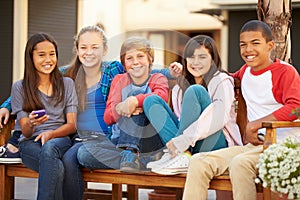 Group Of Children Sitting On Bench In Mall