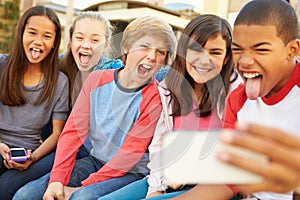 Group Of Children Sitting On Bench In Mall Taking Selfie