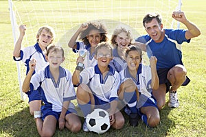 Group Of Children In Soccer Team Celebrating With Trophy