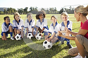 Group Of Children In Soccer Team Having Training With Female Coach