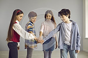 Group of children stand and join hands together studio shot on copy space