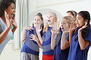 Group Of Children With Teacher Enjoying Drama Class Together