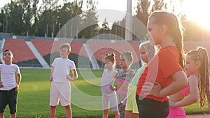 A group of children, on the treadmill at the stadium on a bright sunny day, warm up with the coach before the