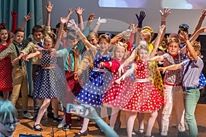 Group of children wearing bright colorful clothes and dancing on the stage.