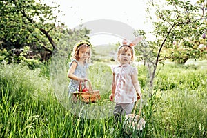 Group Of Children Wearing Bunny Ears Running To Pick Up colorful Egg On Easter Egg Hunt In Garden