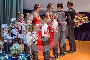 Group of children wearing formal suits and dancing on the stage. Pairs of dancing students.
