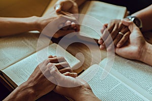 Group of christian people reading and study bible in home and pray together.Group of people holding hands praying worship god.