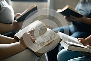 Group of Christian women sat together in chairs, holding their Bibles, feeling the togetherness of prayer and their religious