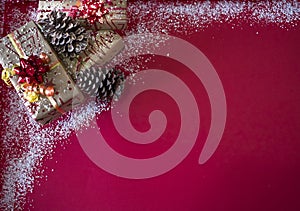 Group of Christmas present and decorations on a red background with white snow. Copy space