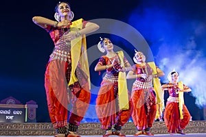 A group of Classical Odissi dancers performing Odissi Dance on stage at Konark Temple, Odisha, India.