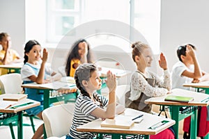 group of classmates raising hands to answer question