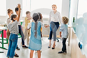 group of classmates standing around teacher at classroom