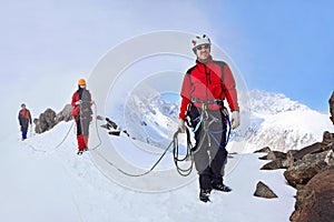 Group of climbers ascent to the mountain on a complex slope is composed of rock and snow