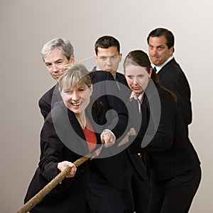 Group of co-workers pulling rope in tug-of-war