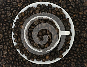 A group of coffee beans in cup and saucer with beans in the background