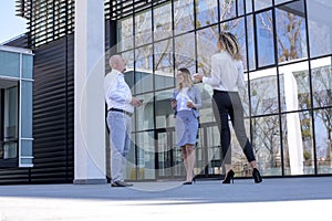 Group of colleagues having a nice conversation during the coffee break outside the office building