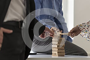 Group of colleagues in an office carefully building a tower of w