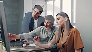 A group of colleagues working on a joint project and have a discussion near a computer. Teamwork concept