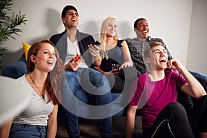 Group Of College Friends Celebrating Whilst Watching Sports Game On TV In Shared House