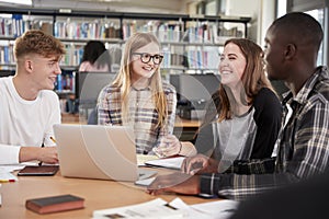 Group Of College Students Collaborating On Project In Library