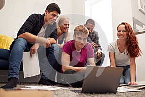 Group Of College Students In Lounge Of Shared House Studying Together