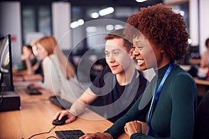 Group Of College Students Studying Computer Design Sitting At Line Of Monitors In Classroom photo