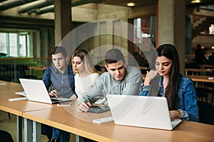 Group of college students studying in the school library, a girl and a boy are using a laptop and connecting to internet