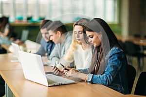 Group of college students studying in the school library, a girl and a boy are using a laptop and connecting to internet