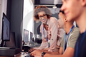 Group Of College Students With Tutor Studying Computer Design Sitting At Monitors In Classroom