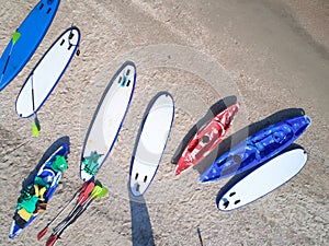 Group of color boards for stand up paddle surfing or SUP lying on beach at sea waves background at summer day