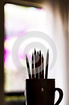 A group of color pencils forming a silhouette in a white cup