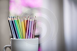 A group of color pencils in a white cup
