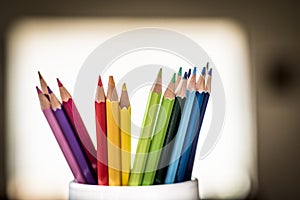 A group of color pencils in a white cup