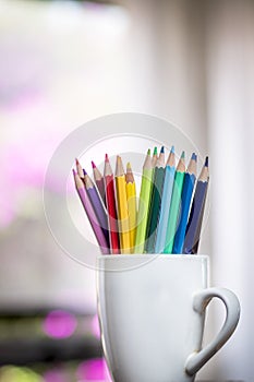A group of color pencils in a white cup