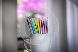 A group of color pencils in a white cup