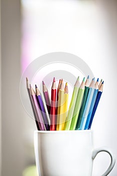 A group of color pencils in a white cup