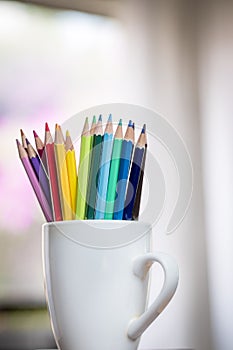 A group of color pencils in a white cup